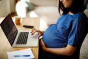 A pregnant woman works on a computer.