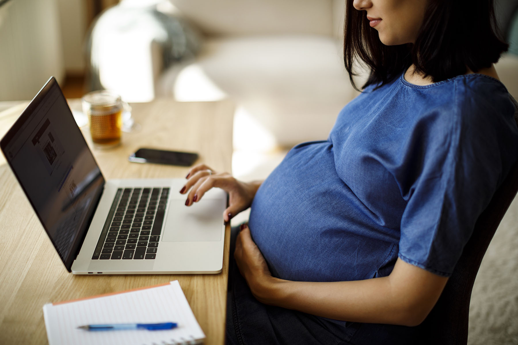 A pregnant woman works on a computer.