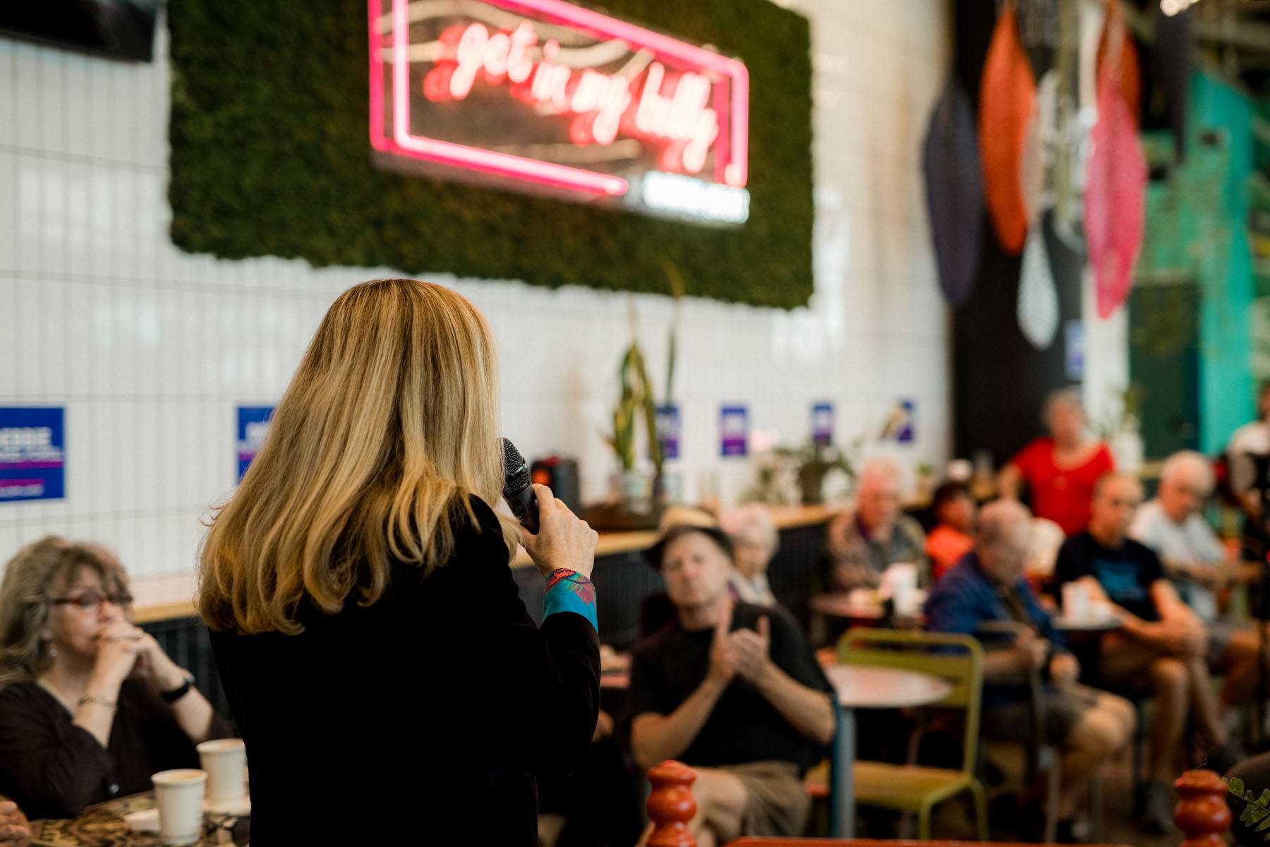 The back of Debbie Mucarsel-Powell's head is seen as she speaks to a crowd in a coffee shop.