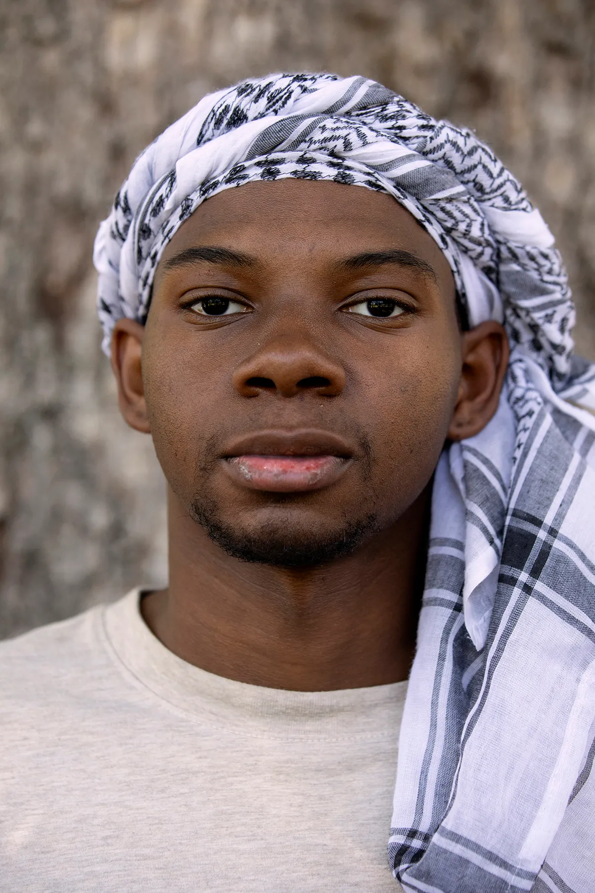 David Hunt poses for a portrait. He is looking at the camera and wearing a keffiyeh around his head.