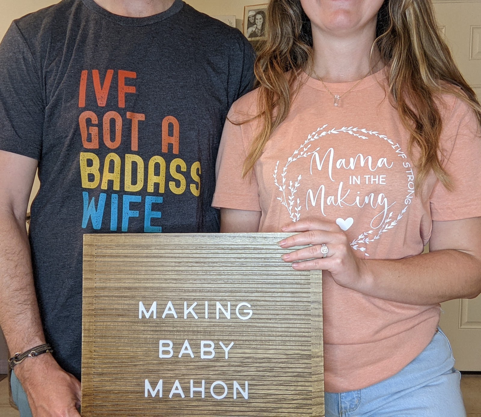 Parents pose with a letter board that reads Making Baby Mahon.