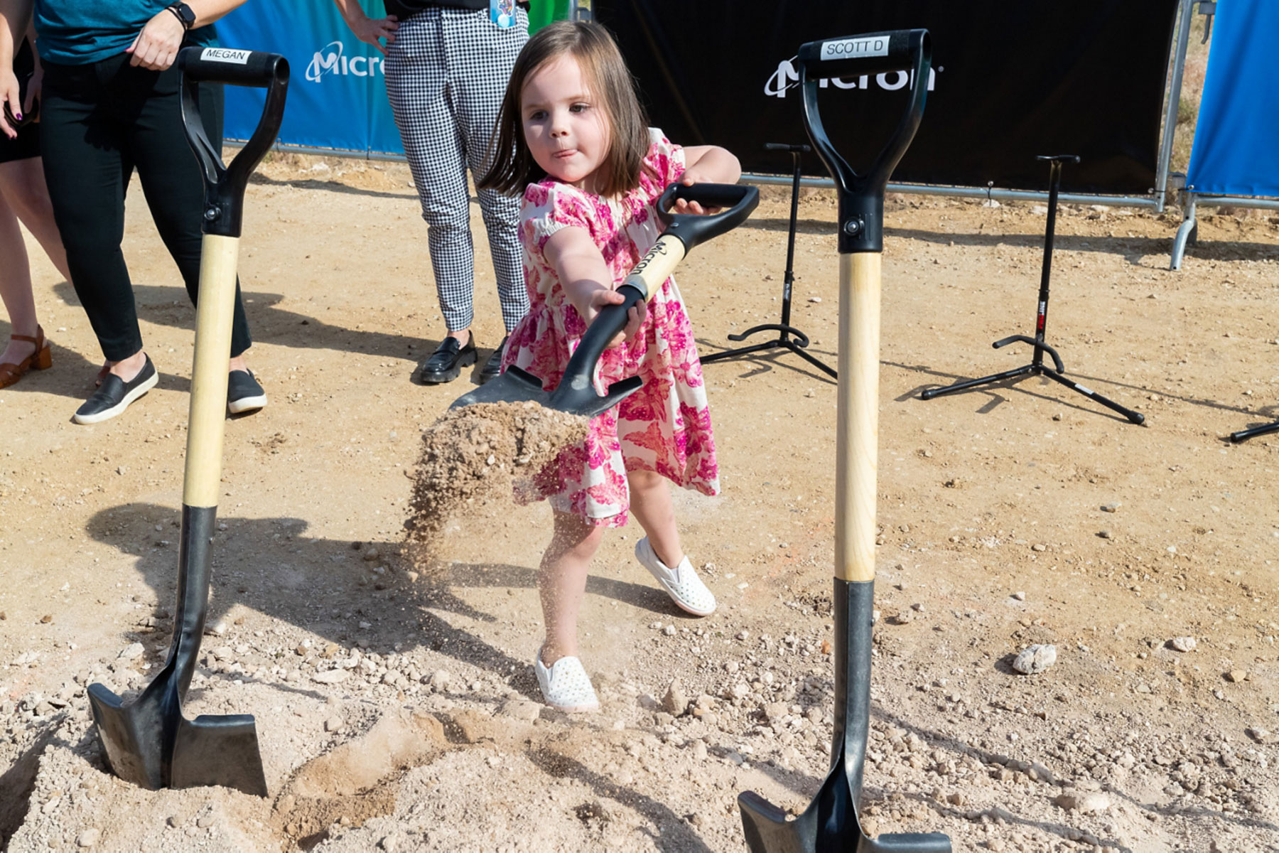 A girl holds a shovel with dirt.