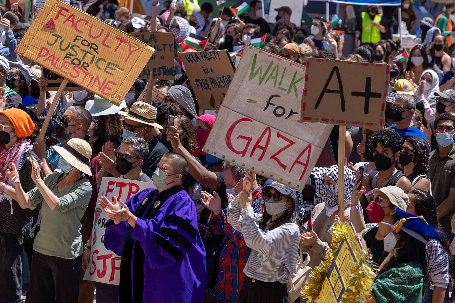 Pro-Palestinian demonstrators hold a student-faculty rally at an encampment on the UCLA campus. Signs read 
