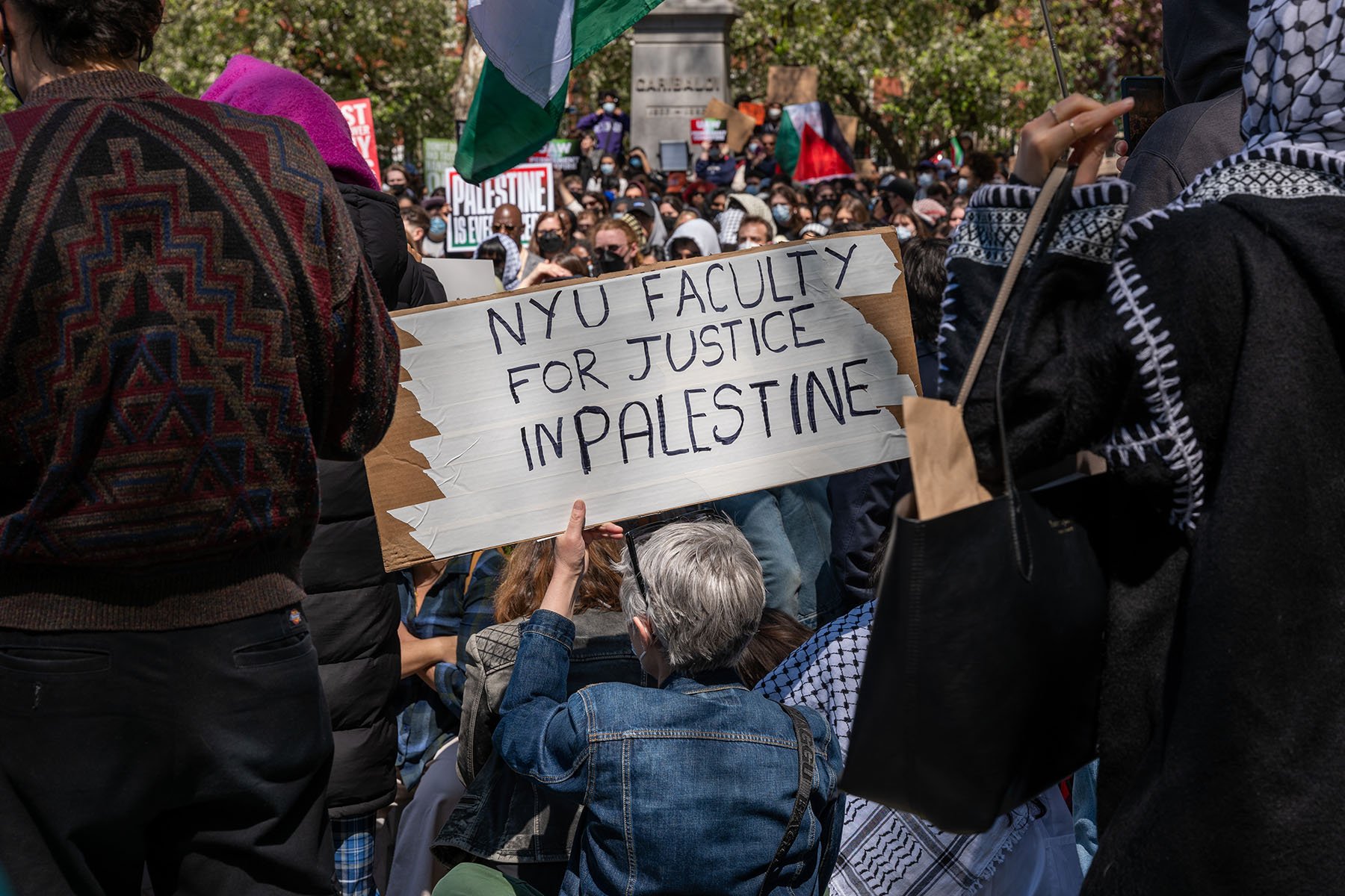 A woman holds a sign that reads "NYU faculty for justice in Palestine" as New York University students and faculty participate in a protest against Israel's war in Gaza.