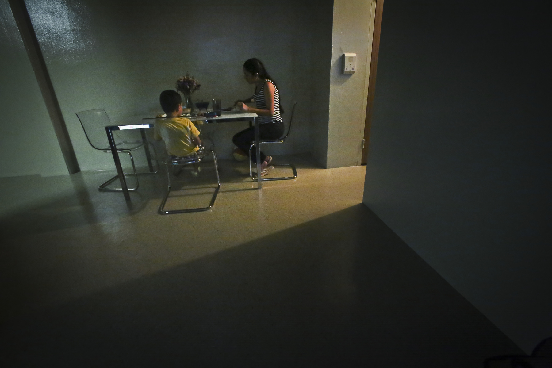A woman sits with her son for dinner in their new, sparsely furnished apartment in New York.