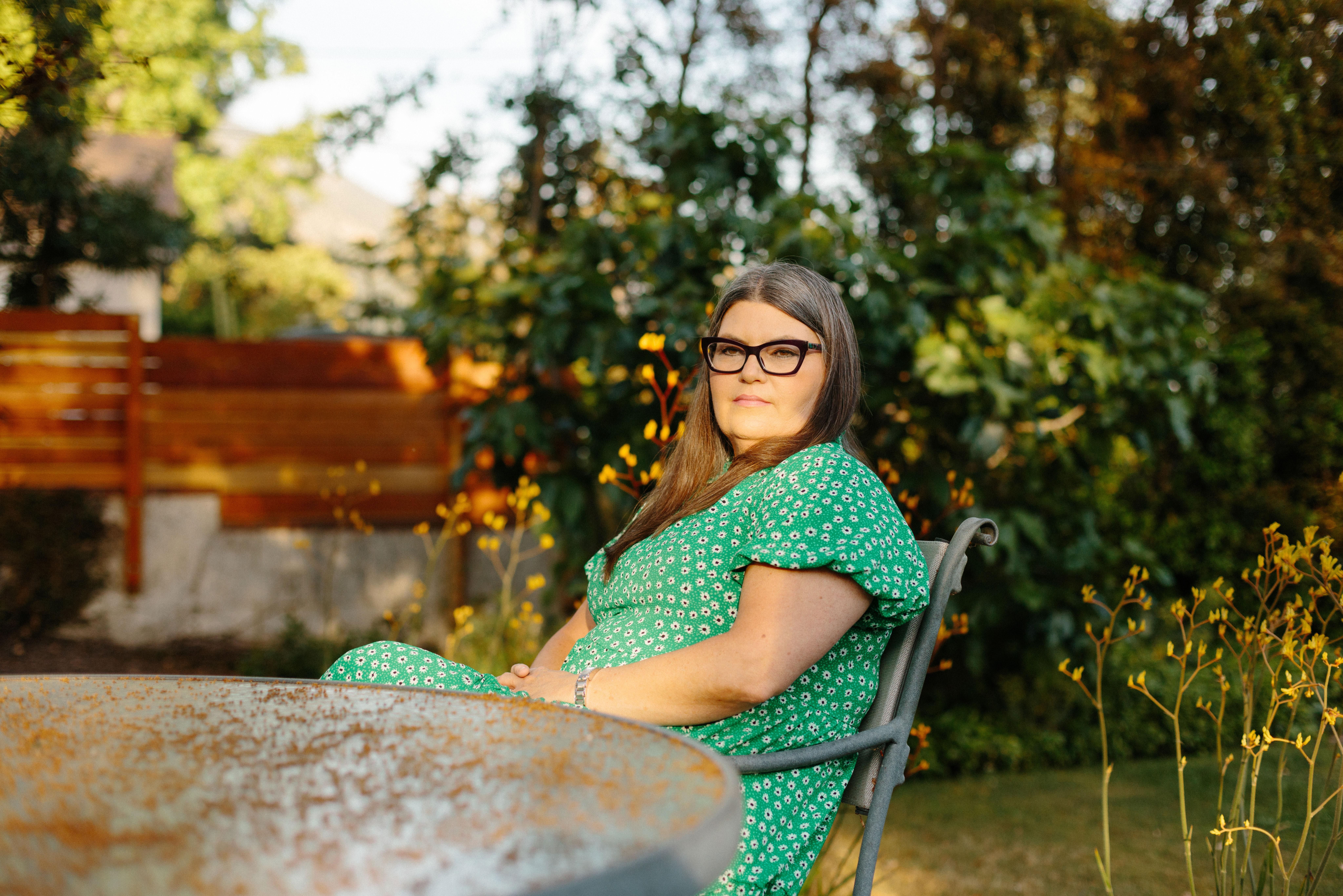 An image of Victoria Knapp sitting at a table in her back yard.