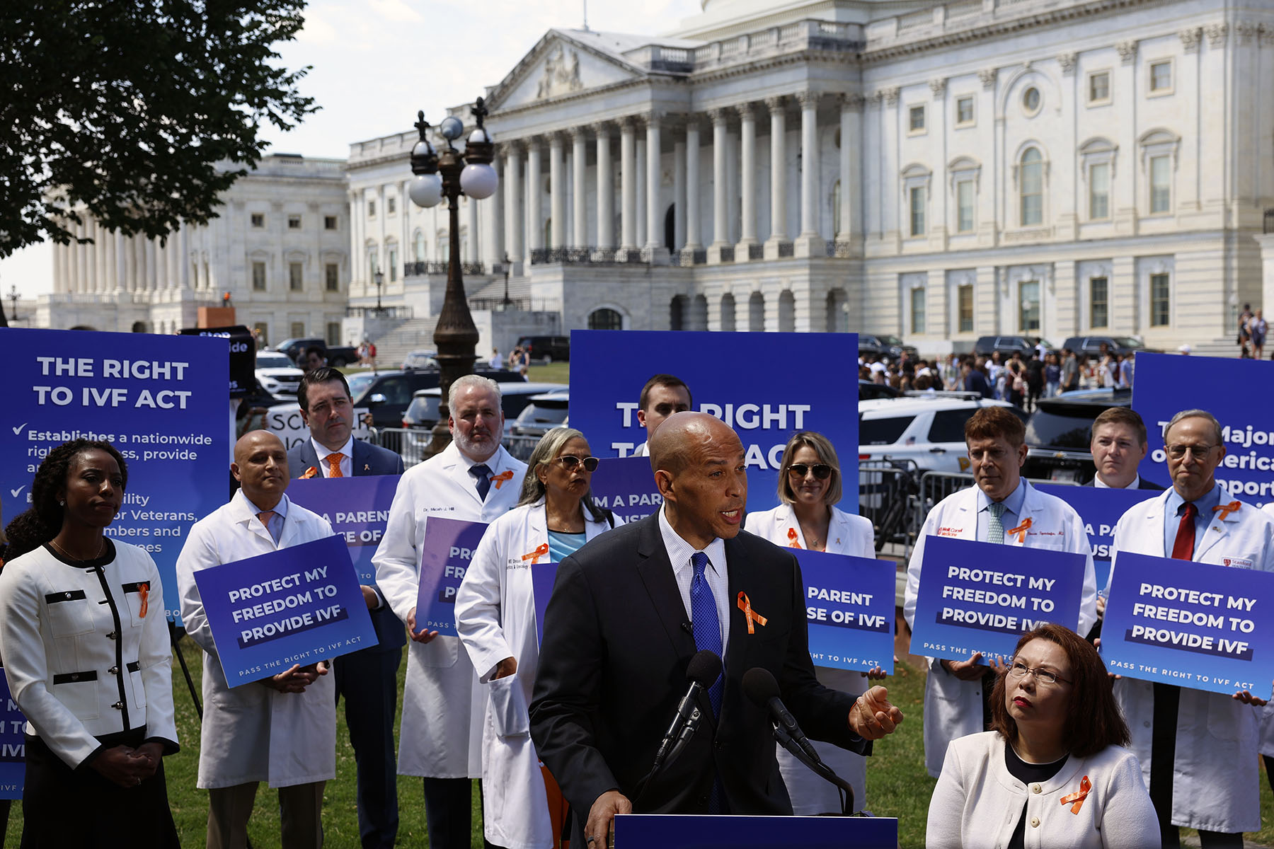 Sen. Cory Booker speaks during a news conference on access to IVF treatments outside of the Capitol Building. He is surrounded by doctors holding signs that read "protect my freedom to provide IVF" and flanked by Sen. Tammy Duckworth