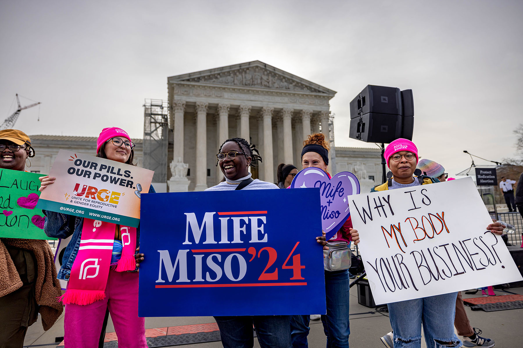 Demonstrators hold signs that read "Mife Miso 2024," "our pills, our power" and "why is my body your business" are seen outside the Supreme Court.
