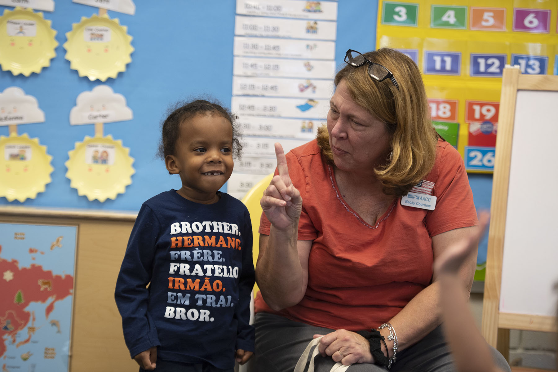 A young child and his teacher are seen at a child care center.
