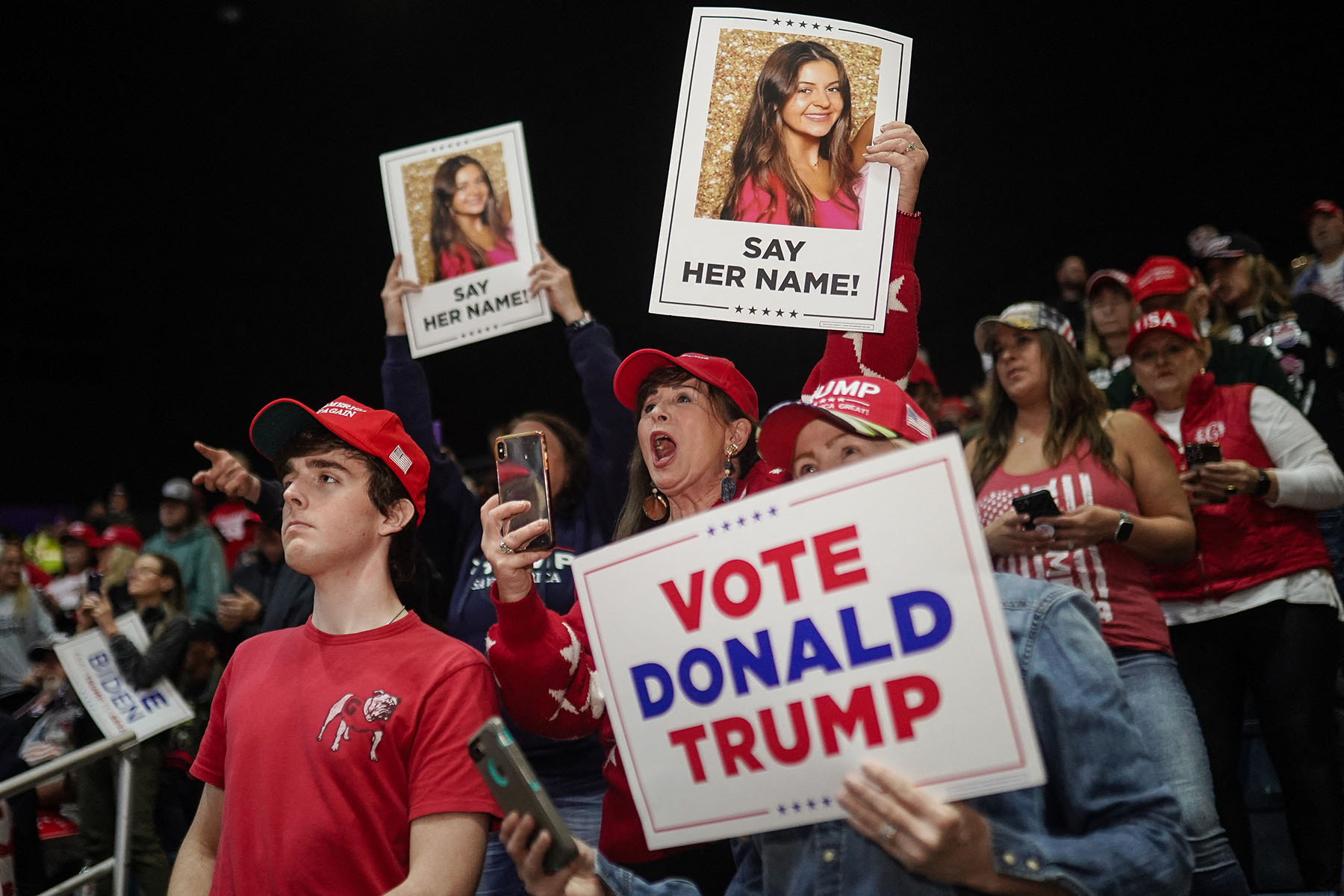 Supporters of former President Trump hold images of Laken Riley before he speaks at a rally.