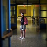 A girl stands in school hallway.