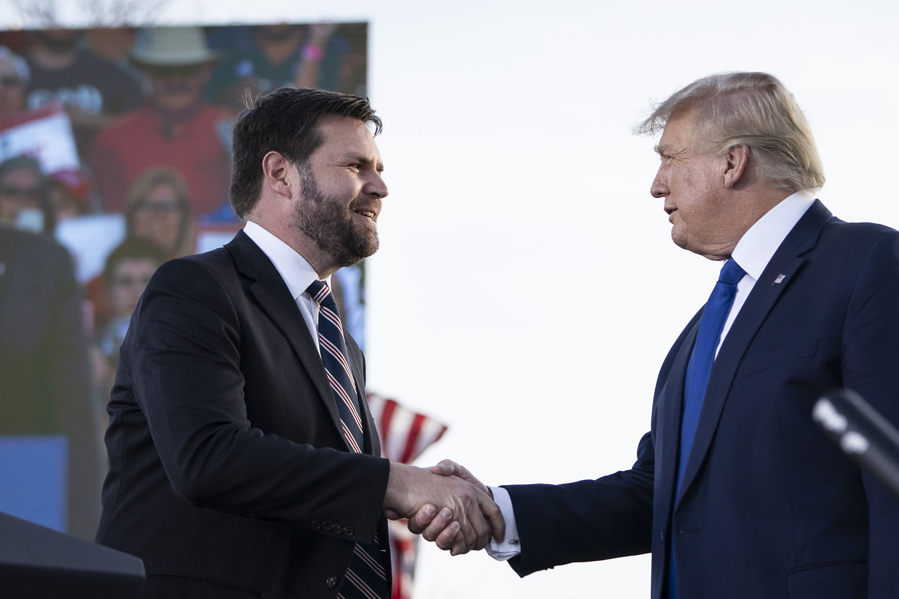 JD Vance shakes hands with former President Donald Trump during a rally.