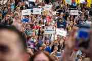 A large crowd of people attend a camapaign event for Vice President Kamala Harris. Several hold up signs that read 