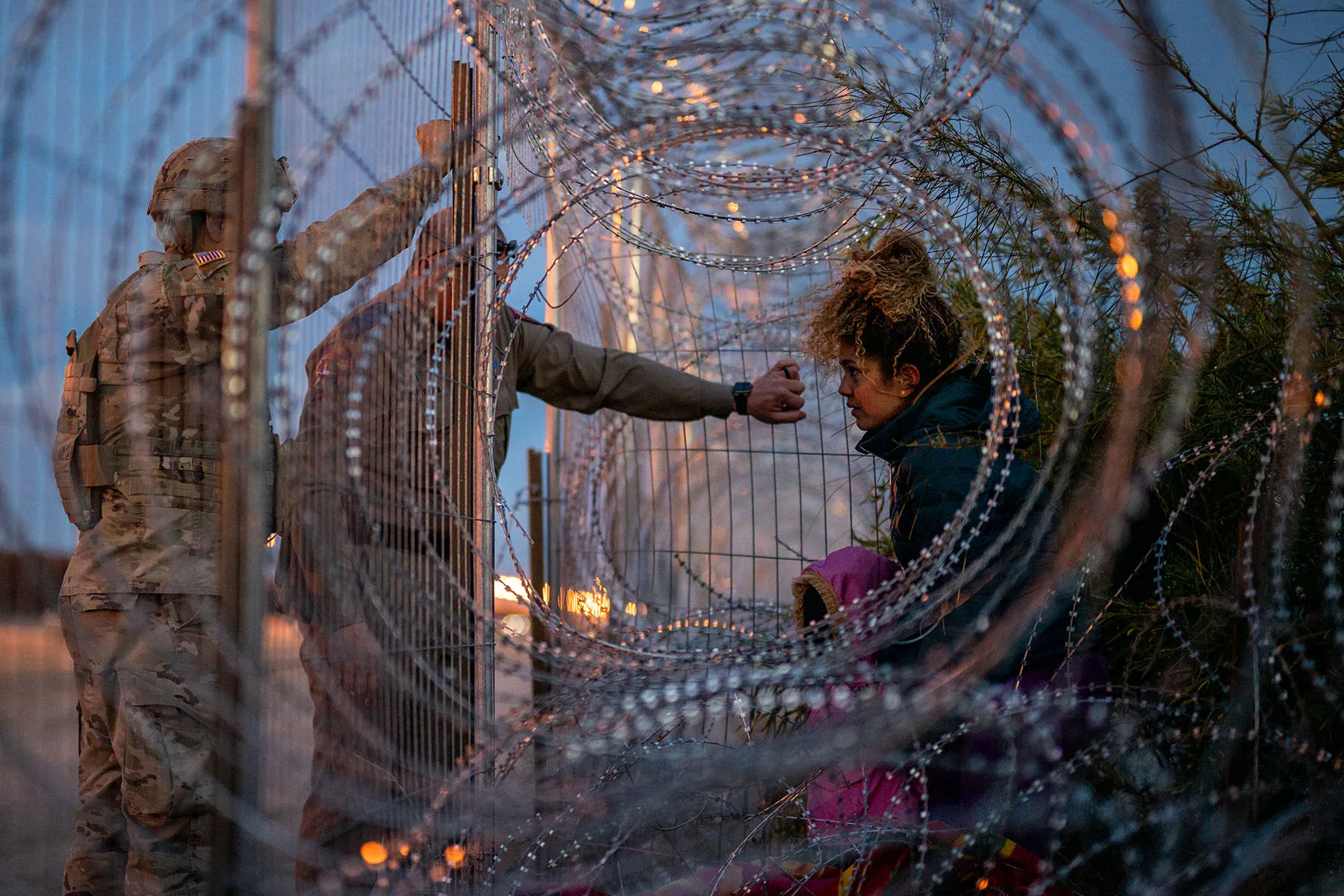 A 22-year-old migrant from Venezuela holds her 3-year-old daughter while being denied entry after attempting to cross through concertina wire.