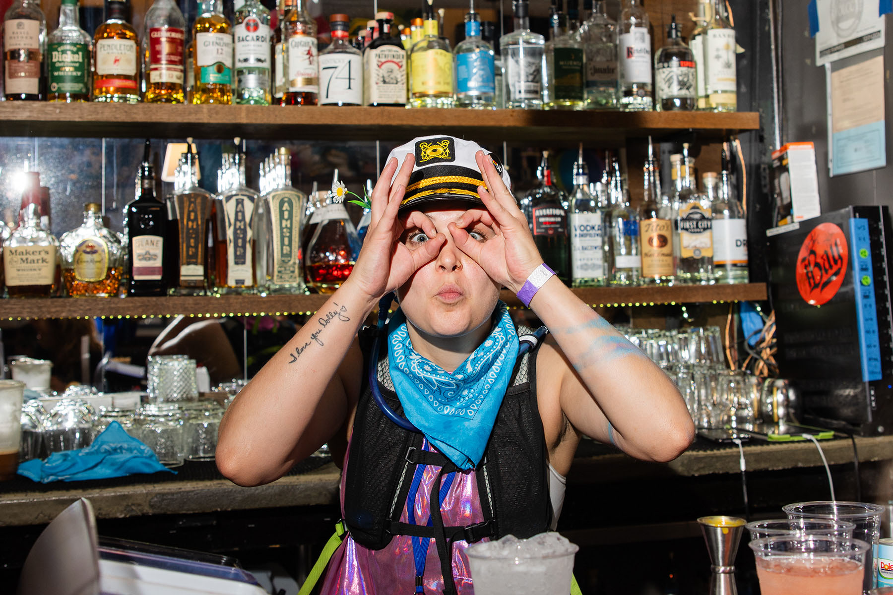 A bartender wearing a captain's makes a silly face as they work at The Sports Bra.