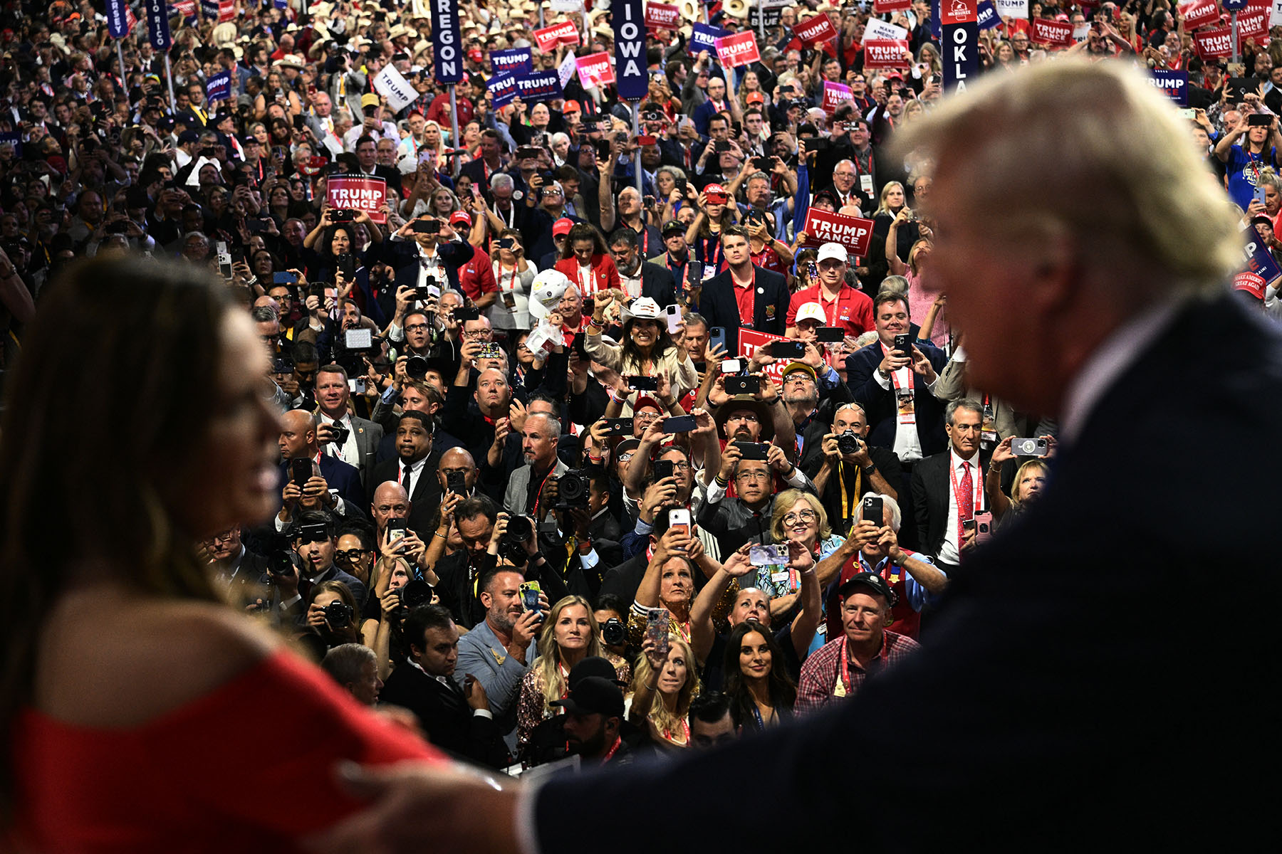 Arkansas Governor Sarah Huckabee Sanders and former President Trump talk as attendees cheer at the Republican National Convention.