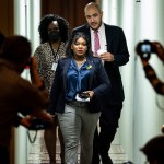 Photographers are seen snapping pictures of Cori Bush leaving the senate chambers after protesting a vote.