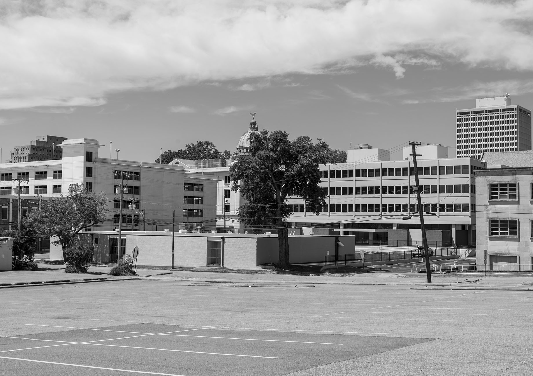 A black-and-white photograph showing a cityscape with several buildings, including one with a dome visible in the distance.