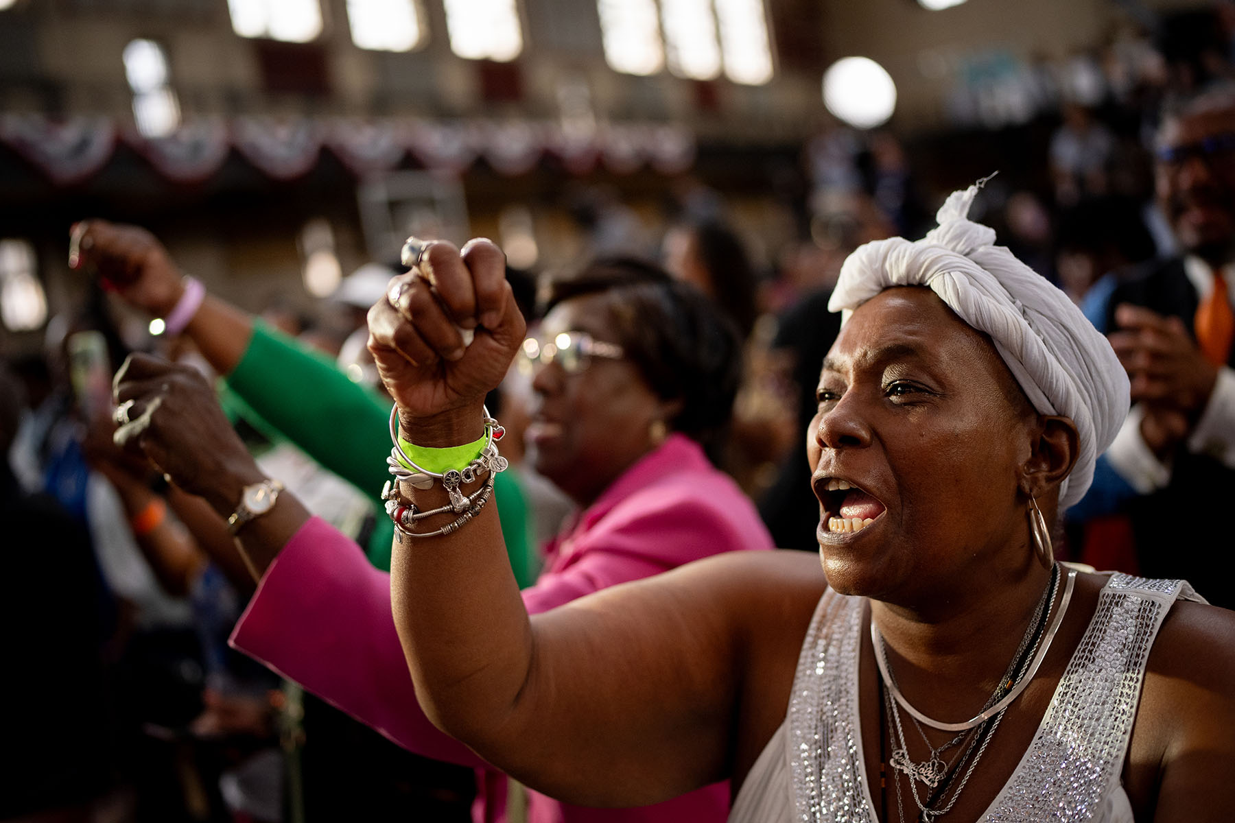 A black woman raises her fist as she cheers during a Biden-Harris campaign rally.