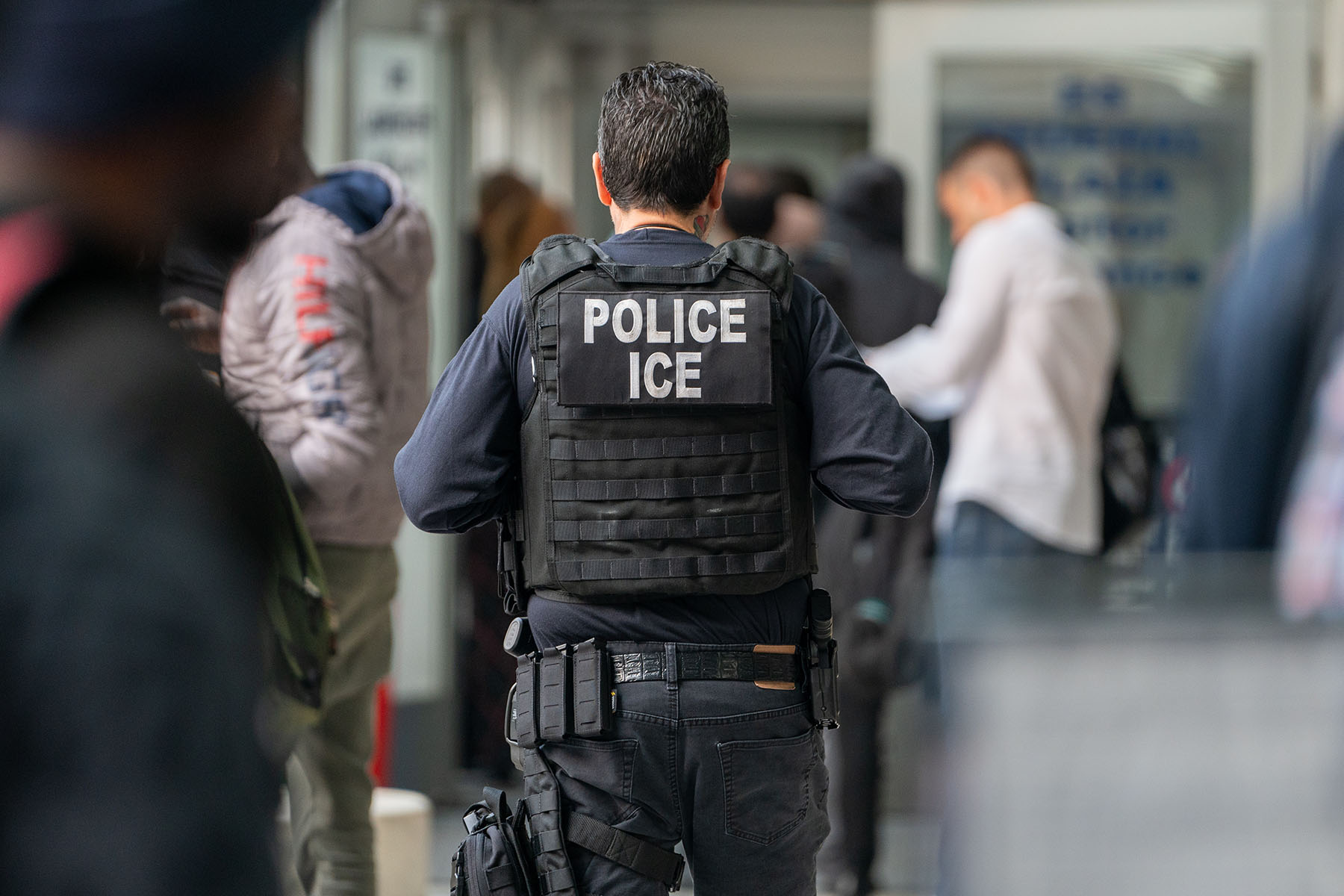 An ICE agent monitors asylum seekers being processed upon entering the Jacob K. Javits Federal Building in New York City.