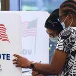 Women wearing face masks fill out vote-by-mail ballots at the Orange County Supervisor of Elections office on October 15, 2020 in Orlando, Florida.