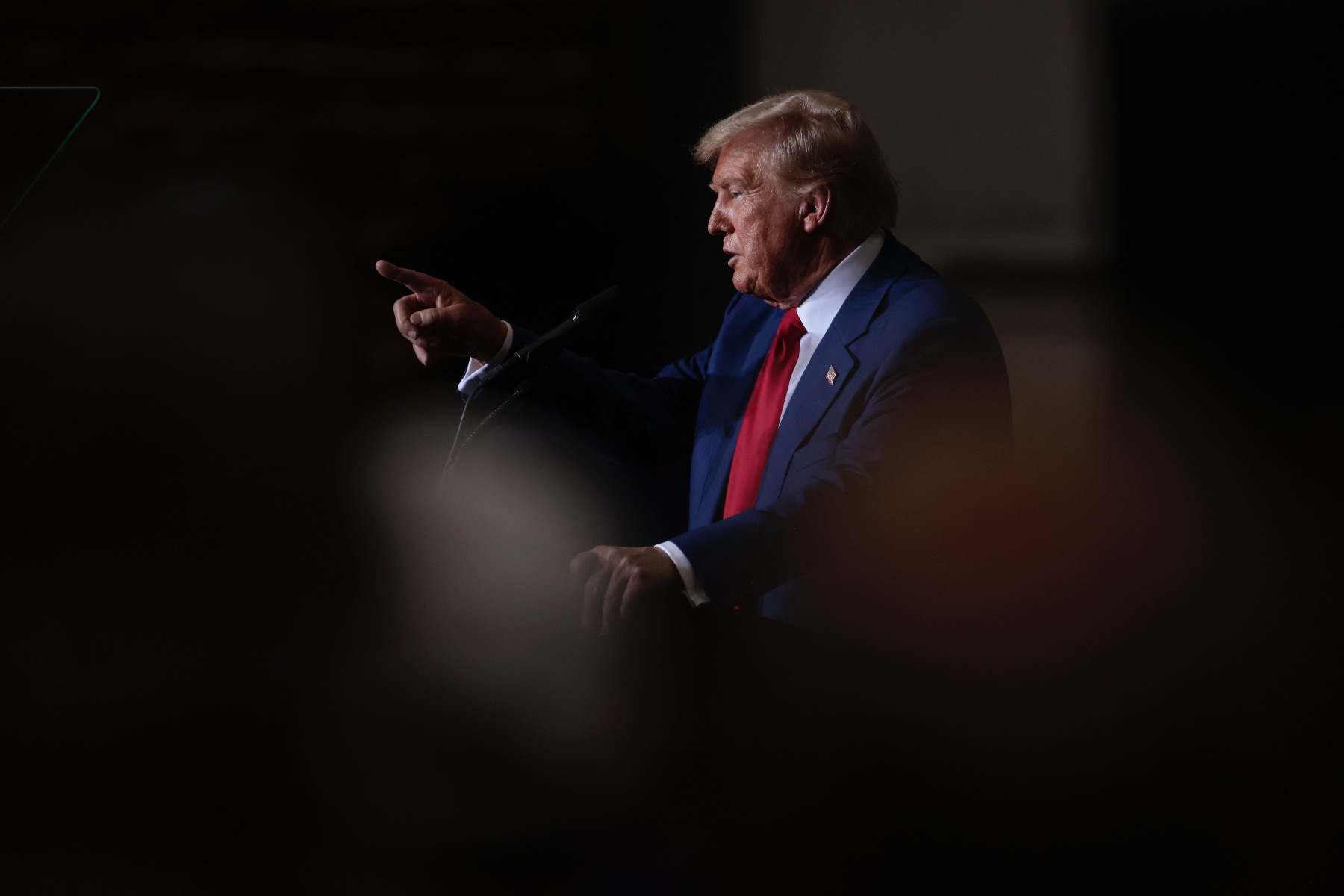 Trump is seen in profile, standing and pointing