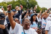 Un grupo de personas levantando la mano y sosteniendo teléfonos celulares durante la Marcha Hablan los Sobrevivientes del Crimen en Washington, DC. Muchos visten camisas blancas con lemas como 