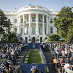 President Joe Biden delivers remarks to celebrate the Americans with Disabilities Act and to mark Disability Pride Month on the South Lawn of the White House. In the foreground, a crowd of diverse attendees, some in wheelchairs, listens to him speak at a podium positioned in the center.