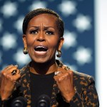 Former First Lady Michelle Obama speaks on stage while campaigning at rally for Vice President Kamala Harris.