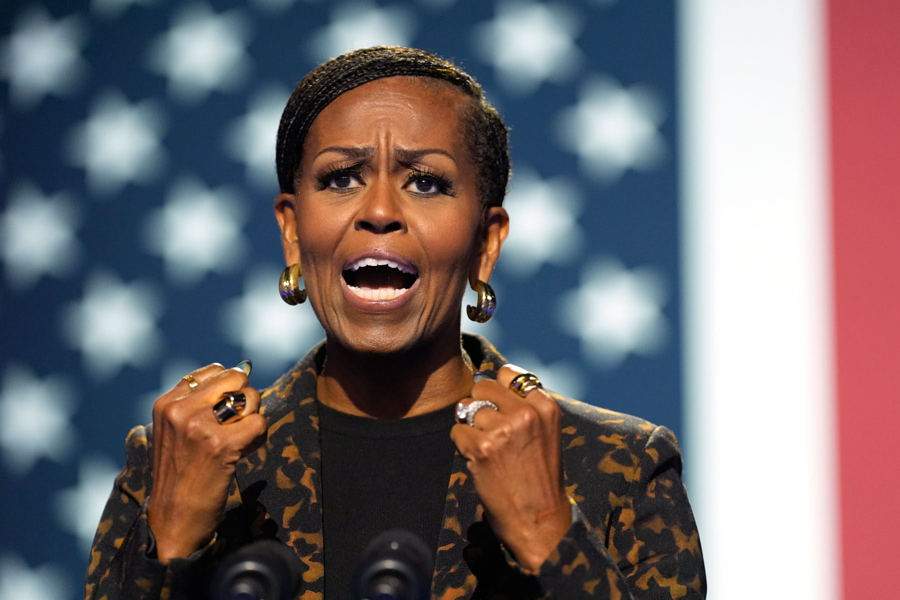 Former First Lady Michelle Obama speaks on stage while campaigning at rally for Vice President Kamala Harris.