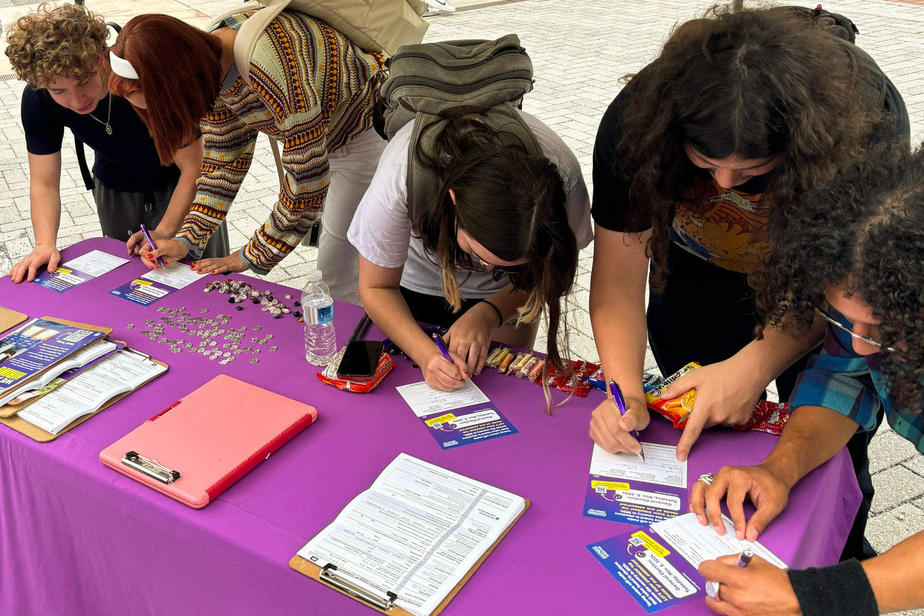 Several students lean over a table filling out voter registration forms.