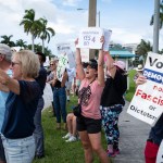 People gather on the sidewalk holding signs supporting abortion rights during a rally in West Palm Beach, Florida, on June 24, 2024.