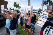 People gather on the sidewalk holding signs supporting abortion rights during a rally in West Palm Beach, Florida, on June 24, 2024.