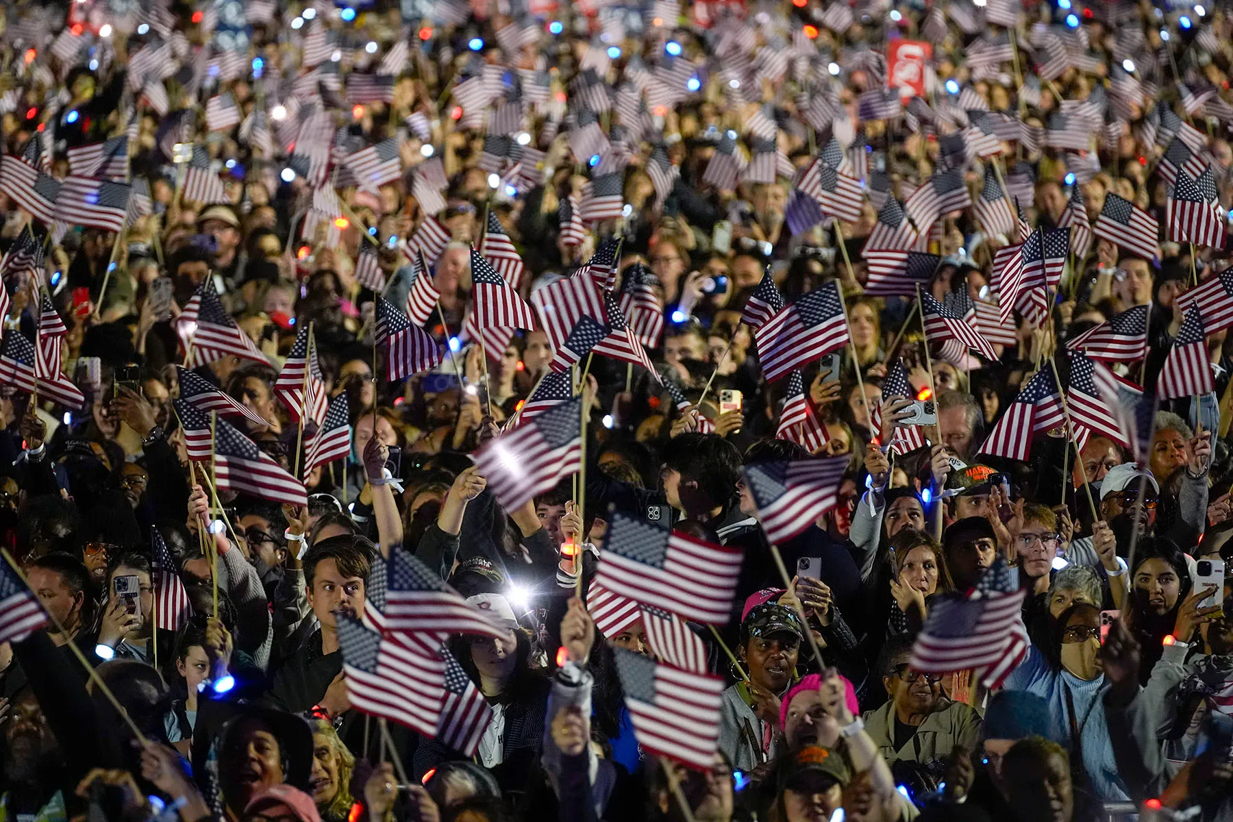 The crowd waves American flags as Vice President Kamala Harris speaks during a campaign rally on the Ellipse in Washington, D.C.