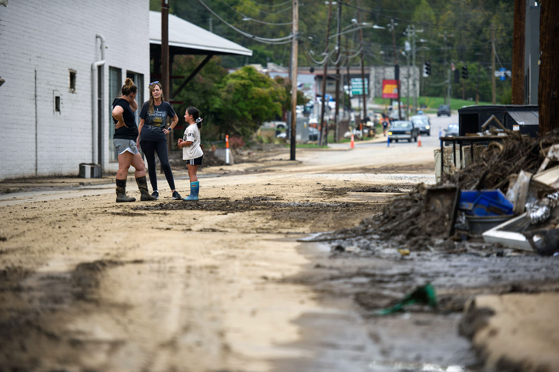 Neighbors speak together downtown while working to remove damaged items and salvage others.