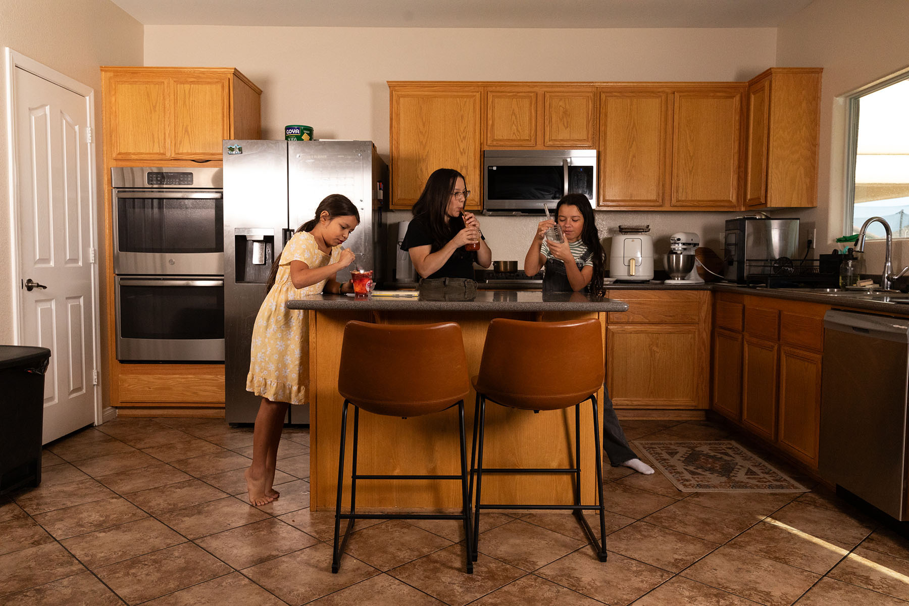 Jasmine Lopez and her two daughters standing in their kitchen, making boba tea together.