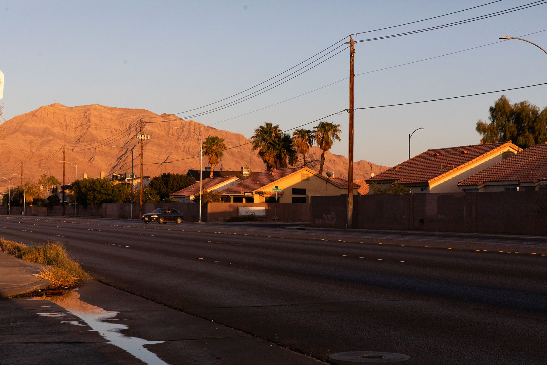 View of a quiet street in Sunrise Manor, with houses and mountains in the background.