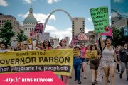 A group of protesters march in downtown St. Louis holding signs that say 