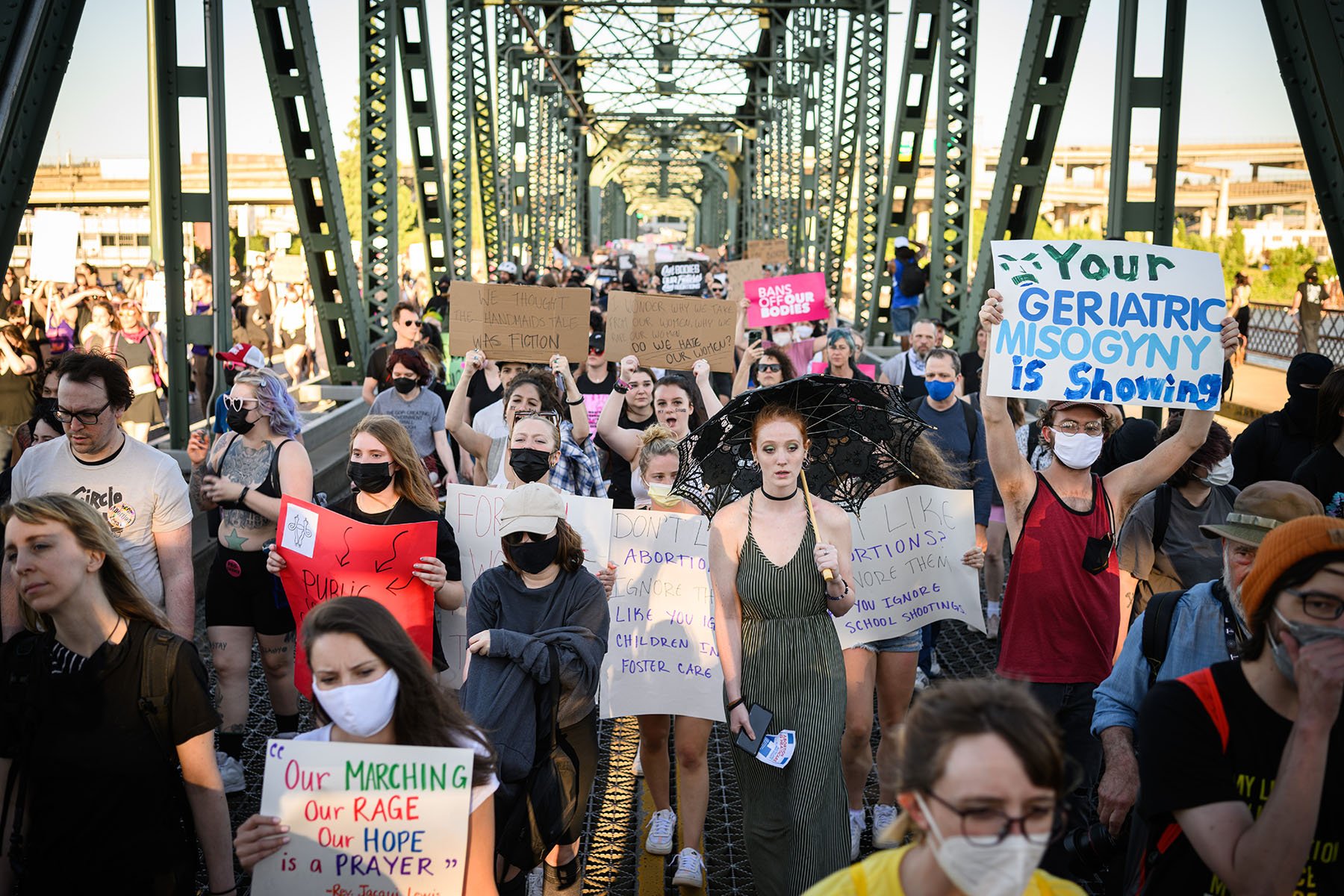 A crowd of people marching across the Hawthorne Bridge in Portland, Oregon, holding signs in protest of the Supreme Court’s decision to overturn Roe v. Wade.