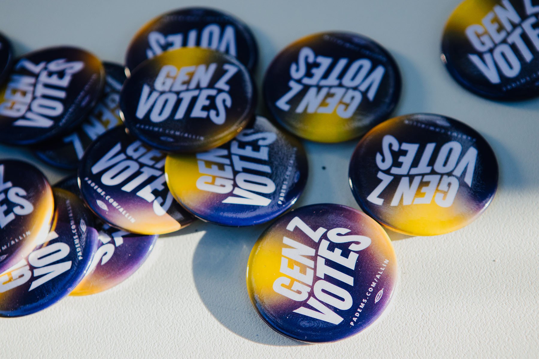 A pile of buttons in purple and yellow hues with the words 'Gen Z Votes' and printed on them.