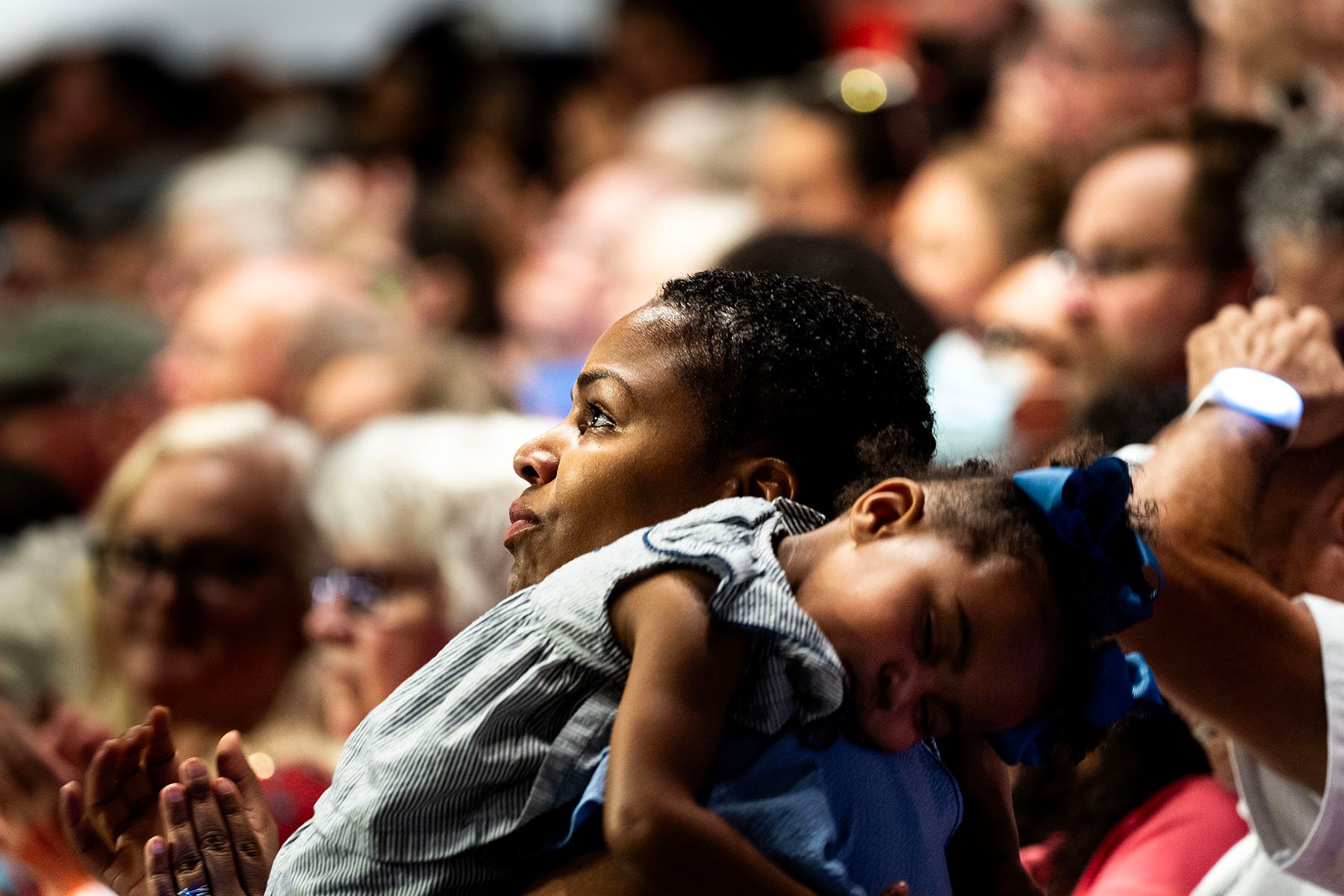 A child sleeps on their mother's shoulder at a Kamala Harris rally in Wisconsin.