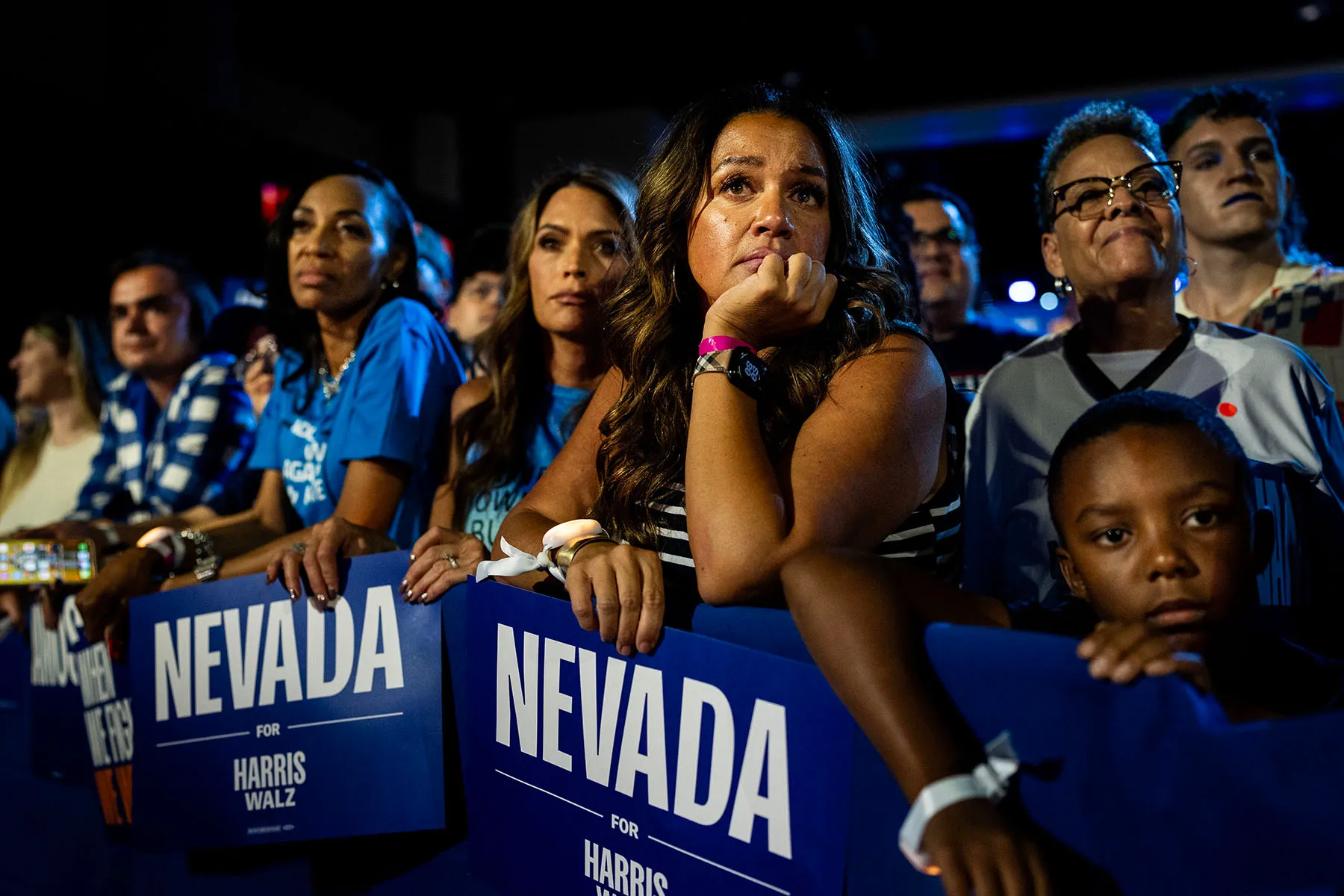 Un grupo de votantes de Nevada en un mitin en Las Vegas, con carteles azules que decían "Nevada para Harris Walz," mientras escucha a Kamala Harris hablar en el escenario.