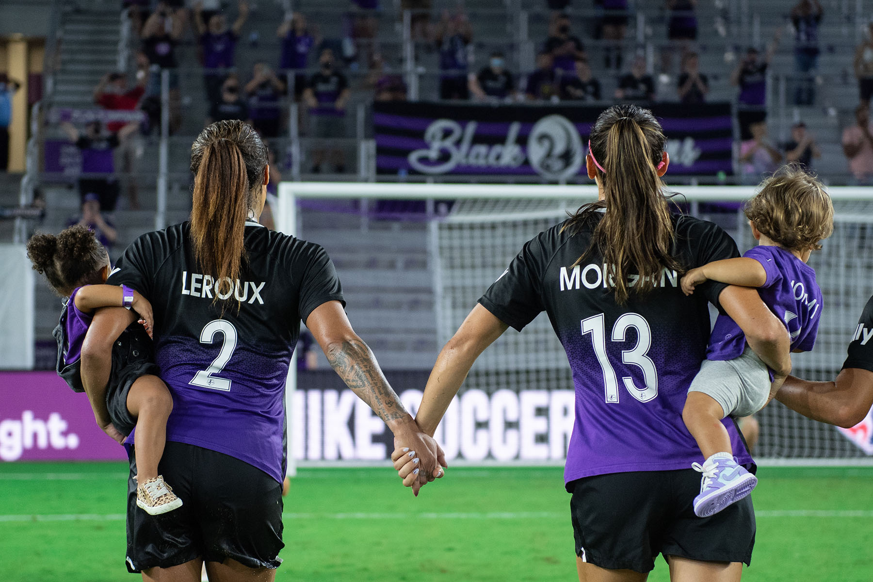 Se ve a Sydney Leroux y Alex Morgan cargando a sus hijos en el campo después de un partido en Orlando, Florida.