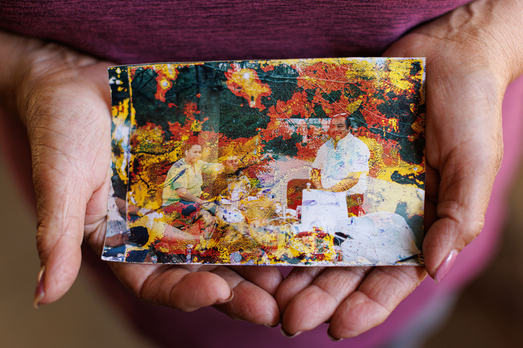 A closeup on a warped printed photograph resting in the palms of a woman's hands.