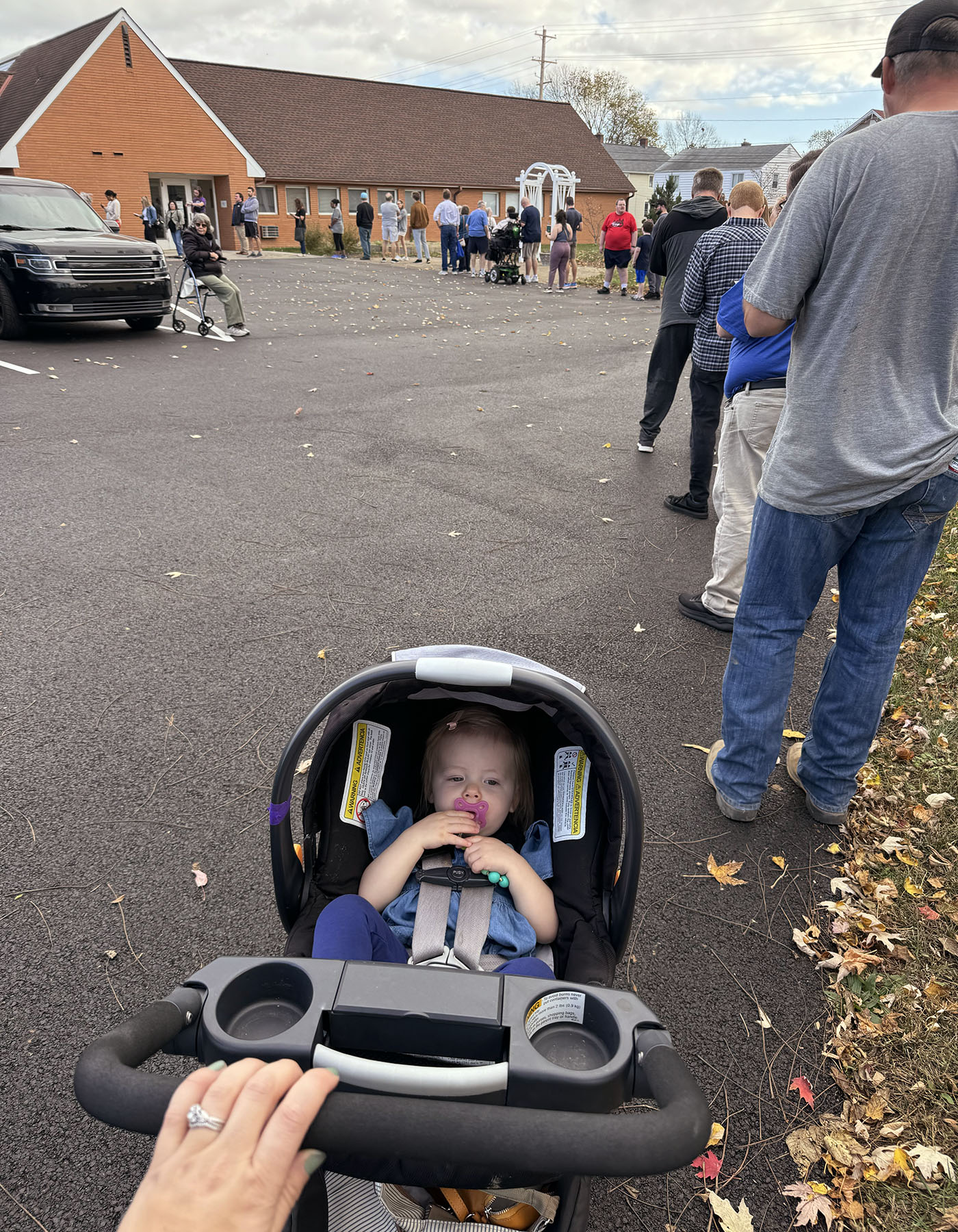 Laura Klarich's 18-month-old daughter is seen in a stroller. In front of them, a long line stretches into a polling station.