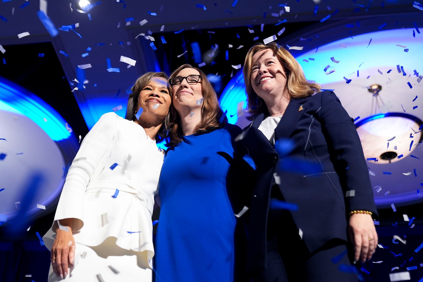 Rep. Lisa Blunt Rochester, Sarah McBride, and Lt. Gov. Elect Kyle Gay embrace on stage during an election night watch party.