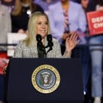 A woman stands behind a podium at a rally.