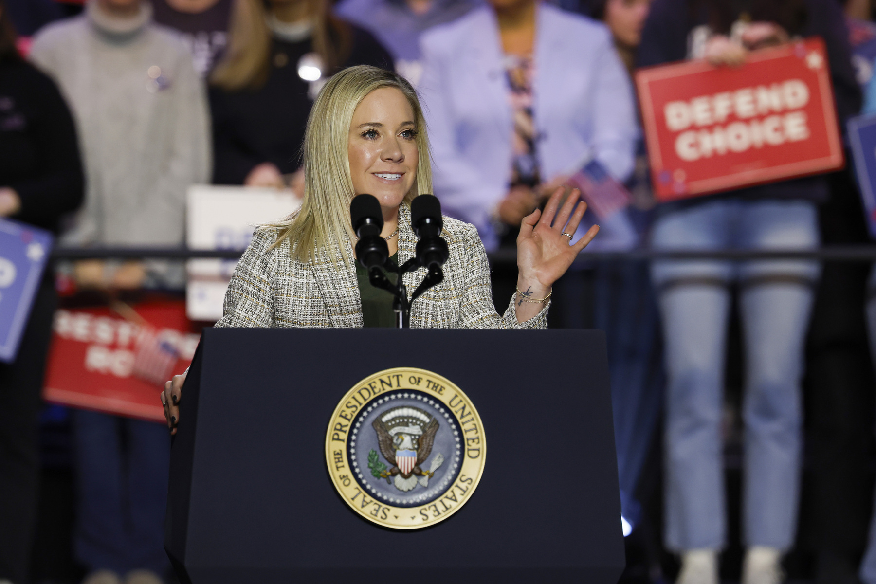 A woman stands behind a podium at a rally.