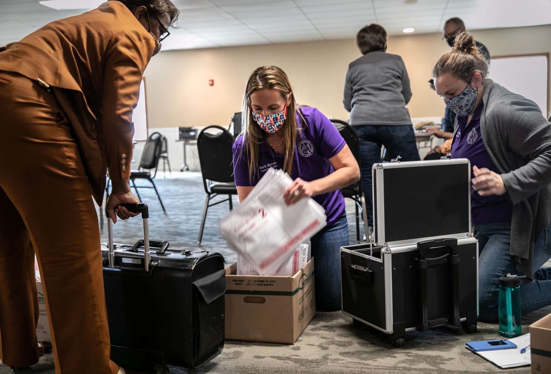 A group of people handle ballot tabulations.