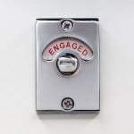 Close-up on bathroom toilet lock indicator in engaged (occupied) position.